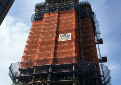 A large construction safety net in place on a high-rise building, protecting workers and the public.